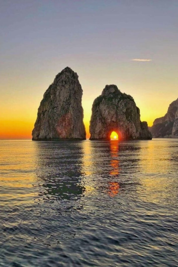 Sunset by boat at Faraglioni Rocks in Capri